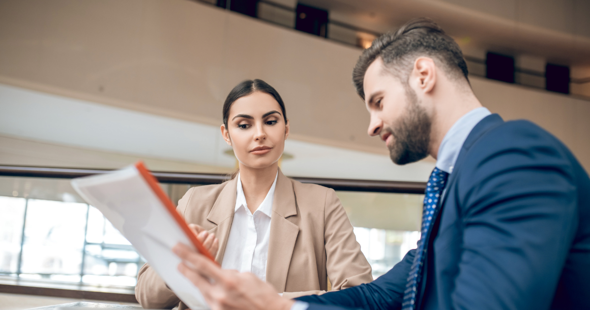 A man and woman in professional attire looking at a piece of paper to show Career Coaching: Bridging Where You are with Where You Want to Go!