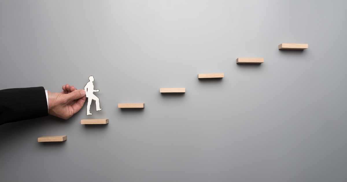 An illustration of someone moving up steps to show Navigating the Leap from Staff-Level to Management: Why You Need a Career Coach